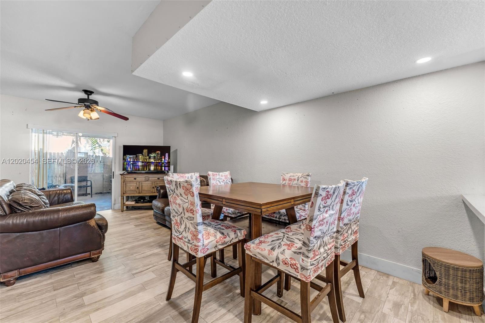 A dining area with floral chairs and a living space featuring a brown leather sofa — 8025 NW 8th St # 13, Miami FL 33126, MIAMI, FL