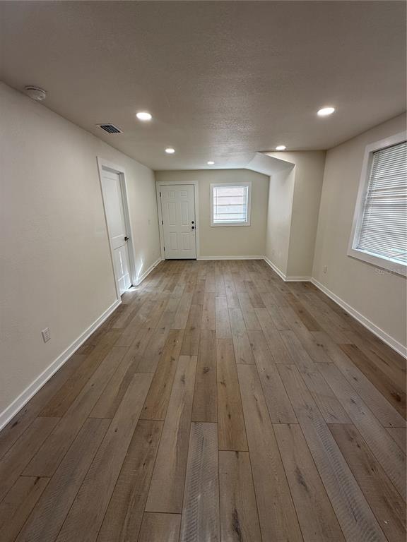 An empty room with light-colored walls, wood-look flooring, recessed lighting, and a white door — 14108 WILSON STREET, DADE CITY, FL