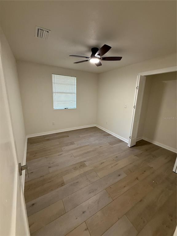 An empty bedroom features light wood-look flooring, a ceiling fan, and a closet doorway — 14108 WILSON STREET, DADE CITY, FL