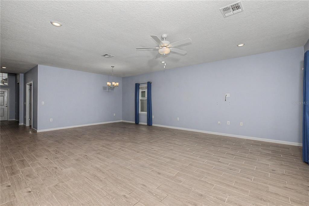 An empty room with light blue walls, wood-look tile flooring, and a ceiling fan — 7795 SW 74TH LOOP, OCALA, FL