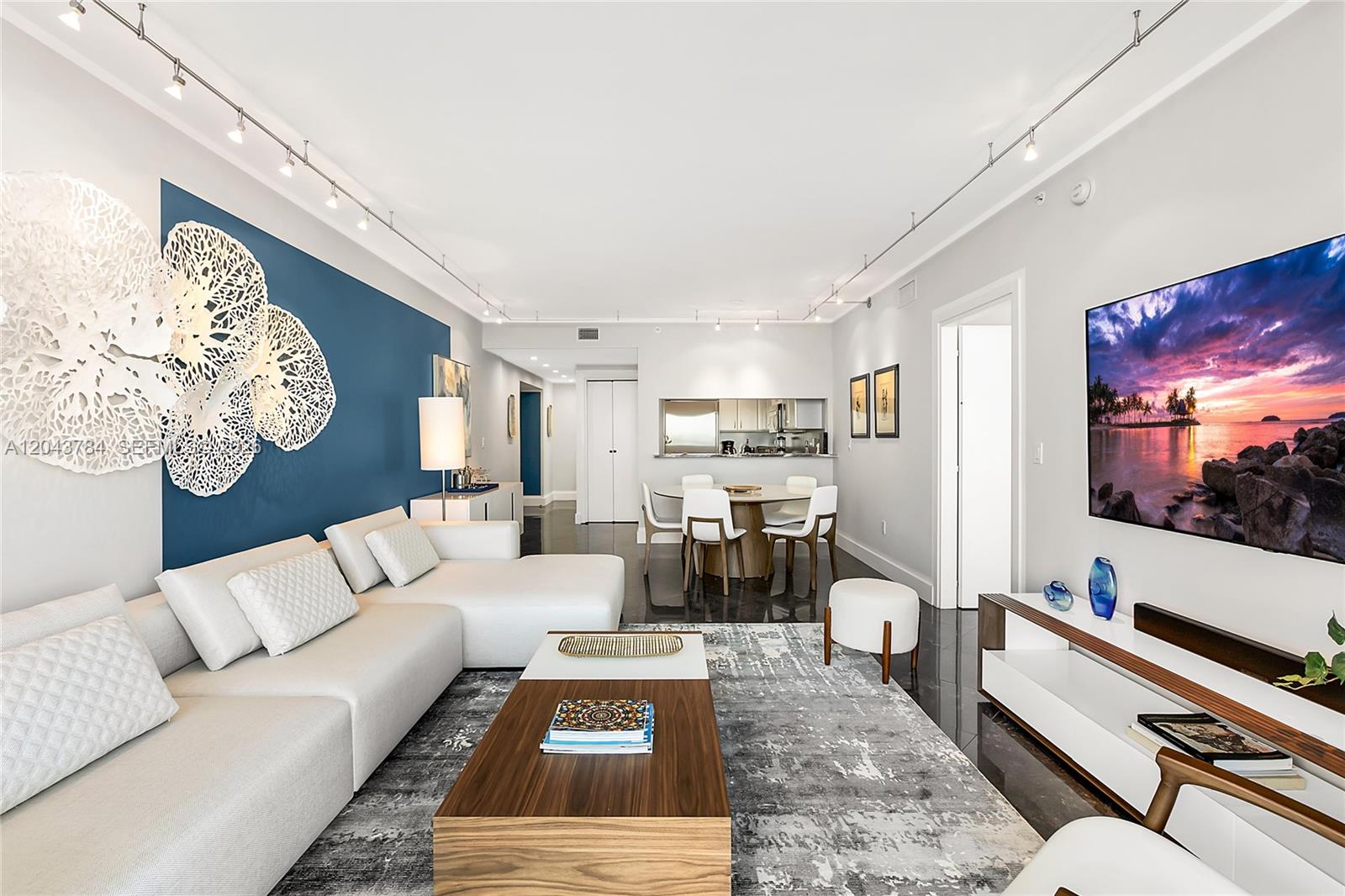 A modern living room features a white sectional sofa, a wooden coffee table, and blue wall — 540 West Ave # 2311, Miami Beach FL 33139, MIAMI BEACH, FL