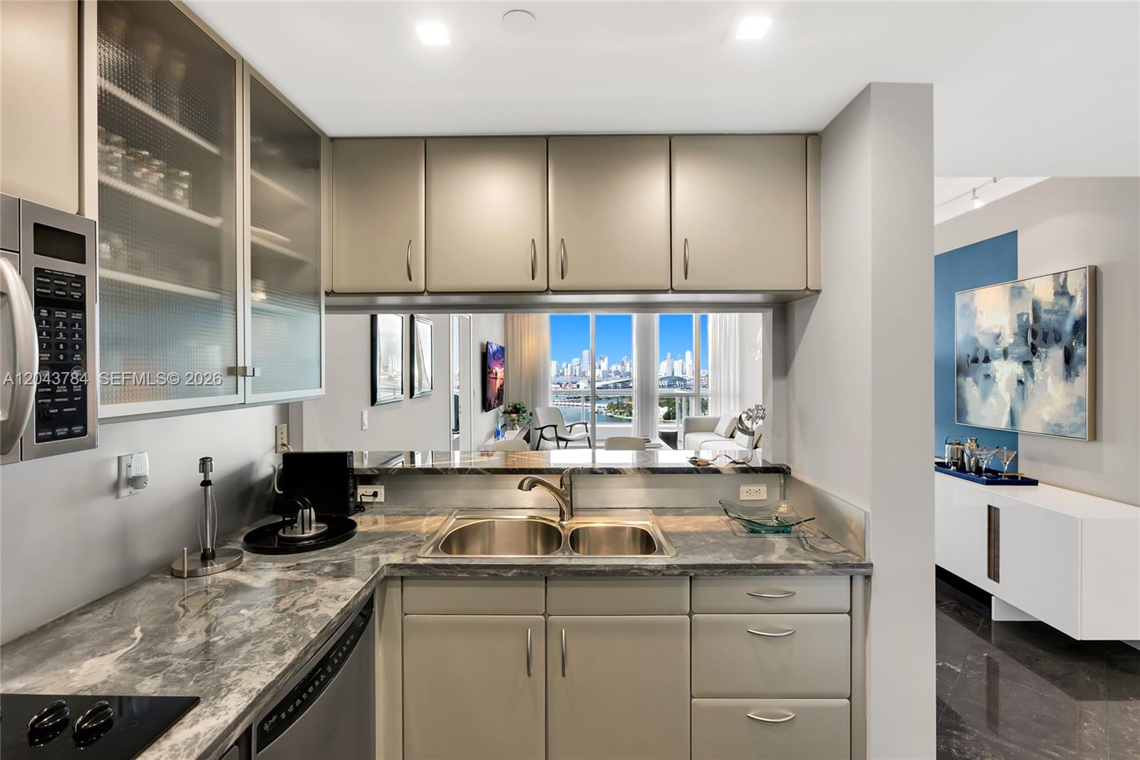 A kitchen with gray cabinets, marble countertops, and a pass-through window overlooking a city skyline — 540 West Ave # 2311, Miami Beach FL 33139, MIAMI BEACH, FL