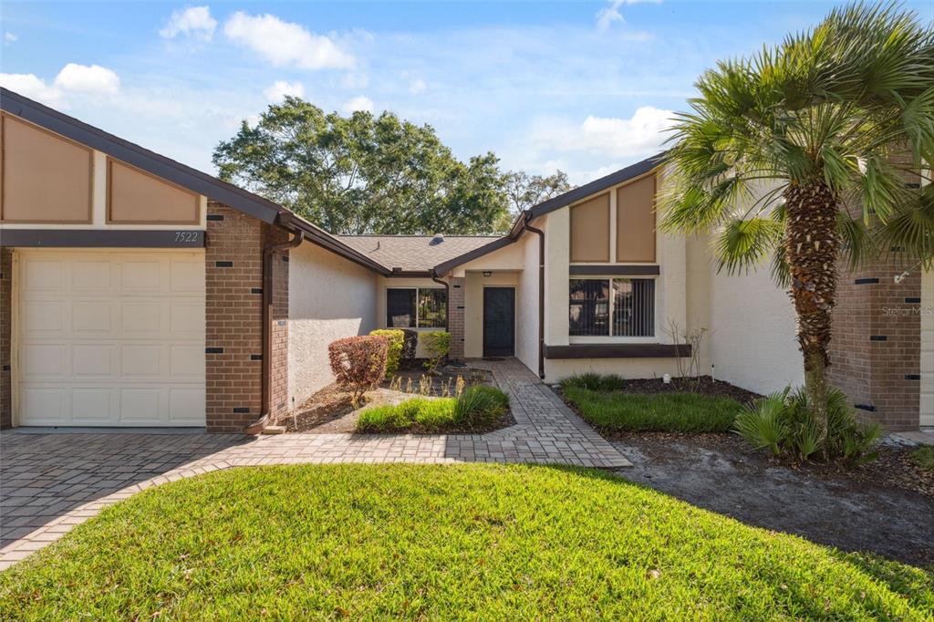 A single-story house with a brick and stucco exterior, a paved walkway, and a palm tree — 7522 HEATHER WALK DRIVE, WEEKI WACHEE, FL