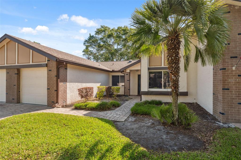 A single-story house with a brick and stucco exterior, a garage, and a palm tree — 7522 HEATHER WALK DRIVE, WEEKI WACHEE, FL