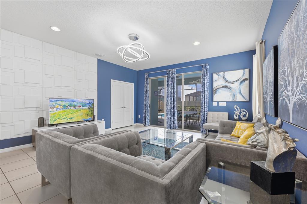 A living room features blue walls, a textured white accent wall, and gray tufted furniture — 8956 ZURICH LANE, KISSIMMEE, FL