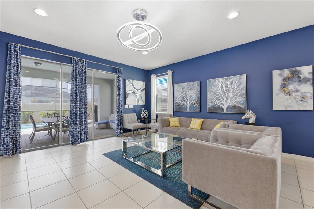 A living room features blue walls, a grey sectional sofa, and sliding glass doors — 8956 ZURICH LANE, KISSIMMEE, FL