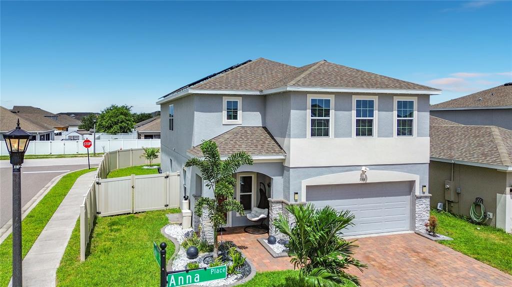 A two-story house with a gray stucco exterior, a brick driveway, and a palm tree — 938 ANNA PLACE, DAVENPORT, FL