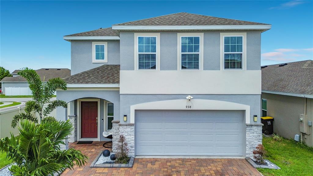 A two-story house with a gray stucco exterior, a two-car garage, and a paver driveway — 938 ANNA PLACE, DAVENPORT, FL