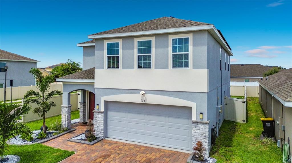 A two-story house with a gray stucco exterior, stone accents, and a two-car garage — 938 ANNA PLACE, DAVENPORT, FL