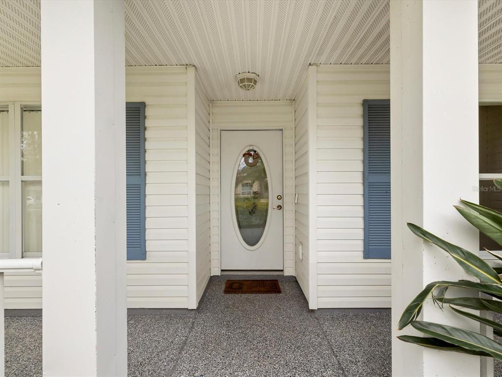 A white front door with an oval glass insert sits under a covered porch — 29146 PRINCEVILLE DRIVE, SAN ANTONIO, FL