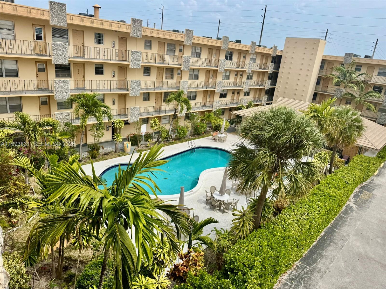 An elevated view of an apartment complex courtyard featuring a swimming pool and palm trees — 2145 Pierce St # 403, Hollywood FL 33020, HOLLYWOOD, FL