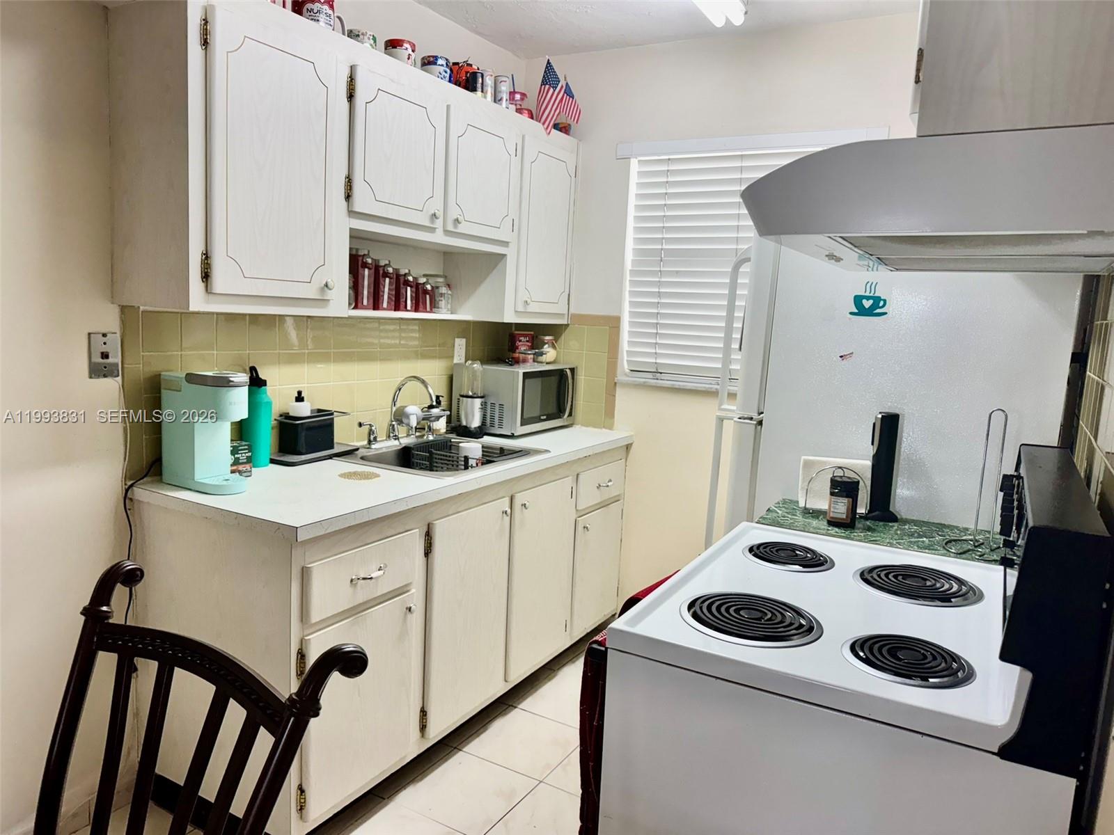 A kitchen features white cabinets, a light-colored countertop, a sink, and a white stove — 2145 Pierce St # 403, Hollywood FL 33020, HOLLYWOOD, FL