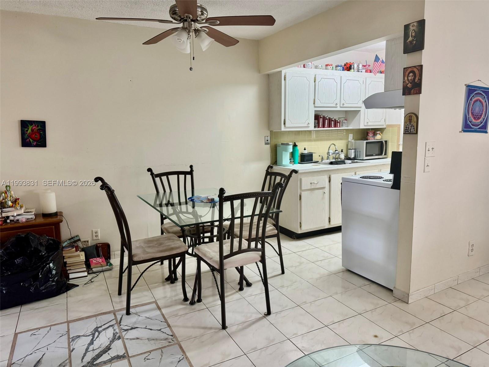 A dining area with a glass table and chairs sits adjacent to a white kitchen — 2145 Pierce St # 403, Hollywood FL 33020, HOLLYWOOD, FL