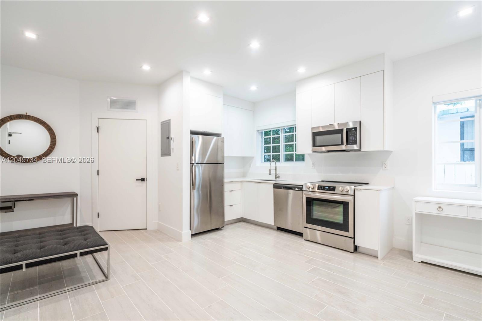 A modern kitchen features white cabinetry, stainless steel appliances, and light-colored tile flooring — 960 Jefferson Ave # 105, Miami Beach FL 33139, MIAMI BEACH, FL