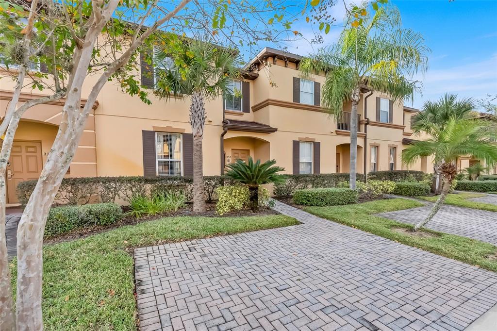 A paved walkway leads to the entrance of a multi-story tan stucco townhouse — 237 VERONA AVENUE, DAVENPORT, FL