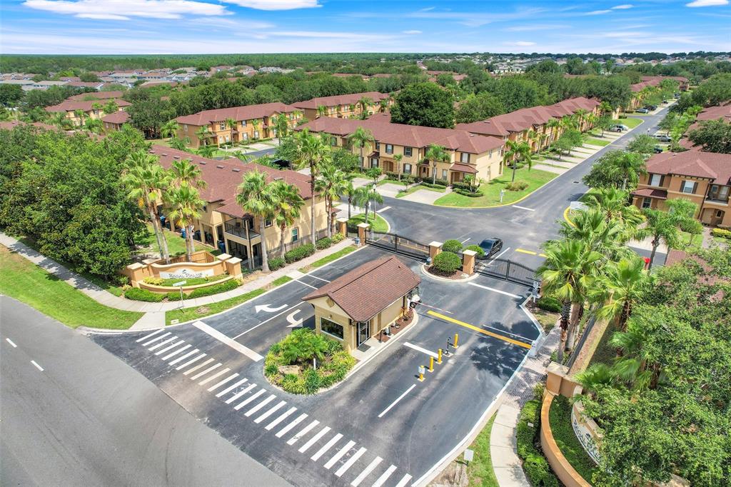 An aerial view shows the gated entrance and surrounding multi-story residential buildings of a community — 237 VERONA AVENUE, DAVENPORT, FL