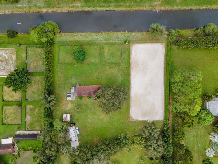 An aerial view shows a house with a large riding arena and fenced paddocks — 16693 Deer Path Lane, Wellington FL 33470, WELLINGTON, FL