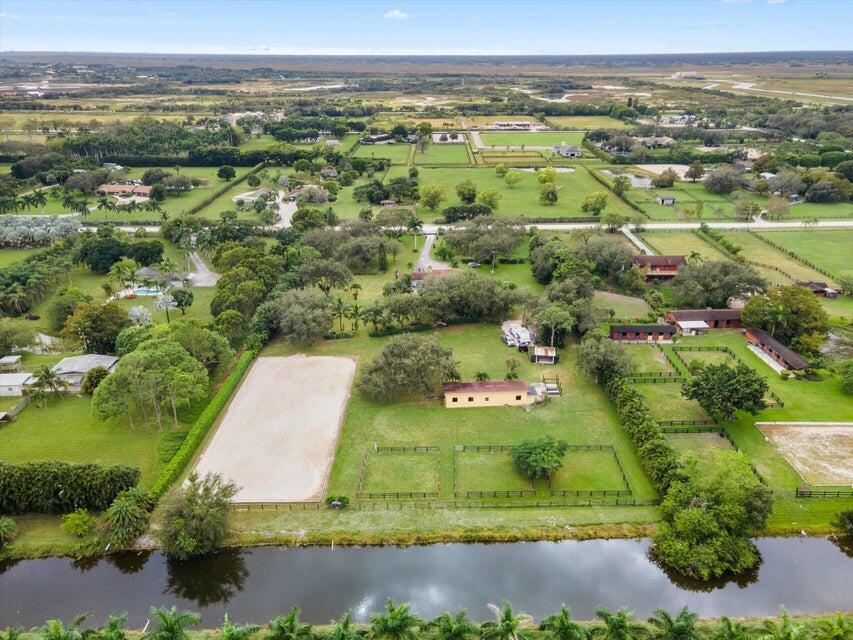An aerial view of a rural property featuring a riding arena, stables, and a canal — 16693 Deer Path Lane, Wellington FL 33470, WELLINGTON, FL