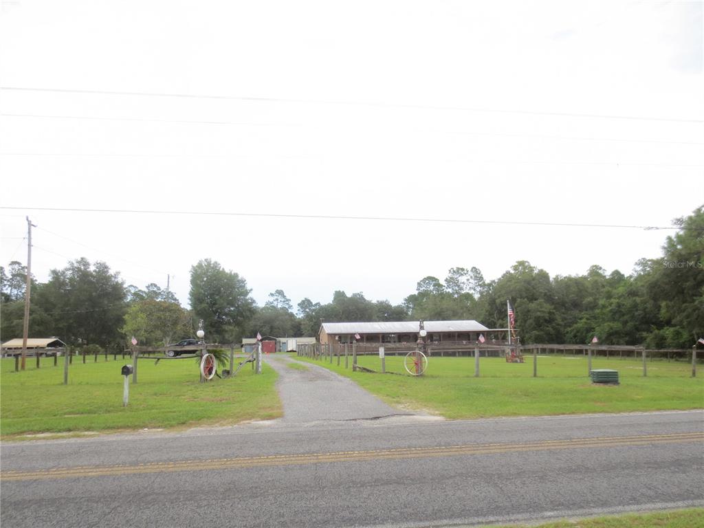 A single-story house with a large front porch sits behind a fenced yard and driveway — 5995 SE 183RD AVENUE ROAD, OCKLAWAHA, FL