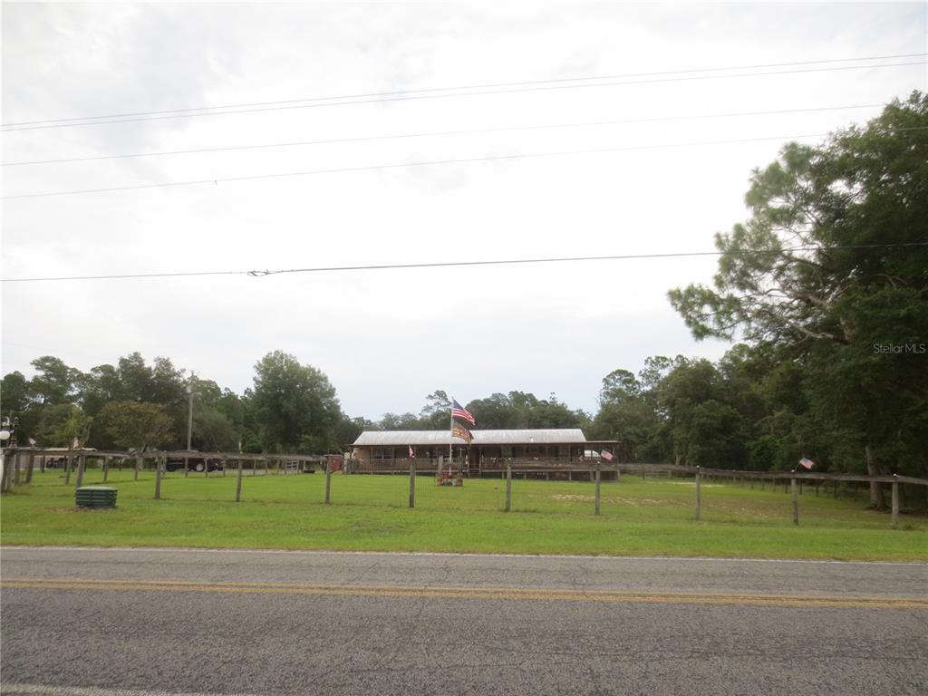 A single-story house with a covered porch sits behind a wooden fence and lawn — 5995 SE 183RD AVENUE ROAD, OCKLAWAHA, FL