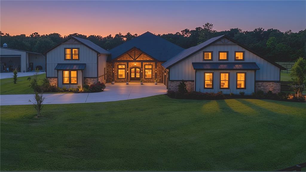 A modern farmhouse with stone accents and a large concrete driveway at twilight — 121 ASHTON OAKS DRIVE, ST AUGUSTINE, FL