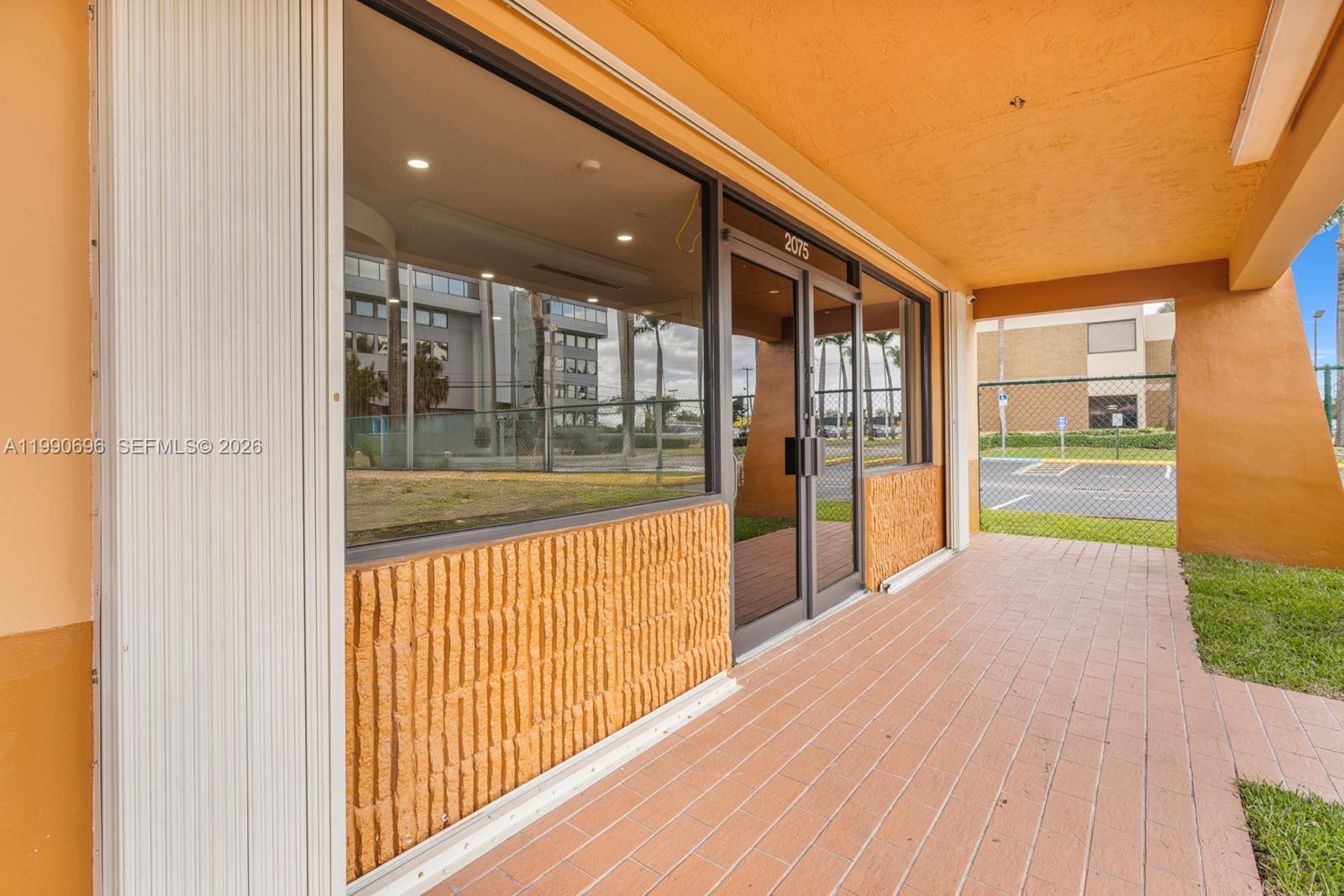 This exterior view shows a commercial storefront entrance with a tiled walkway and glass doors — 2075 W 76th St # 1, Hialeah FL 33016, HIALEAH, FL