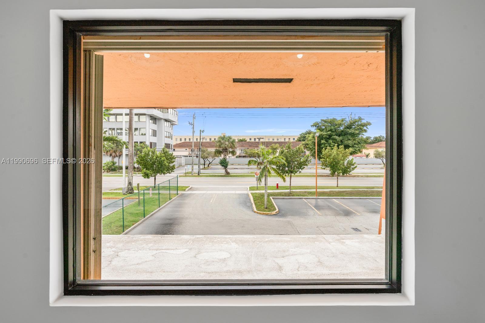 A view through a window shows a parking lot, palm trees, and a street — 2075 W 76th St # 1, Hialeah FL 33016, HIALEAH, FL