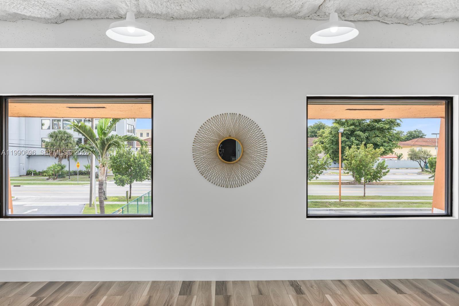 A room with two windows, a sunburst mirror, and pendant lights over wood-look flooring — 2075 W 76th St # 1, Hialeah FL 33016, HIALEAH, FL