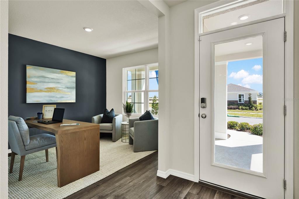 A home office with a dark accent wall, wooden desk, and two chairs near an entryway — 5150 MARSHELDER STREET, APOPKA, FL