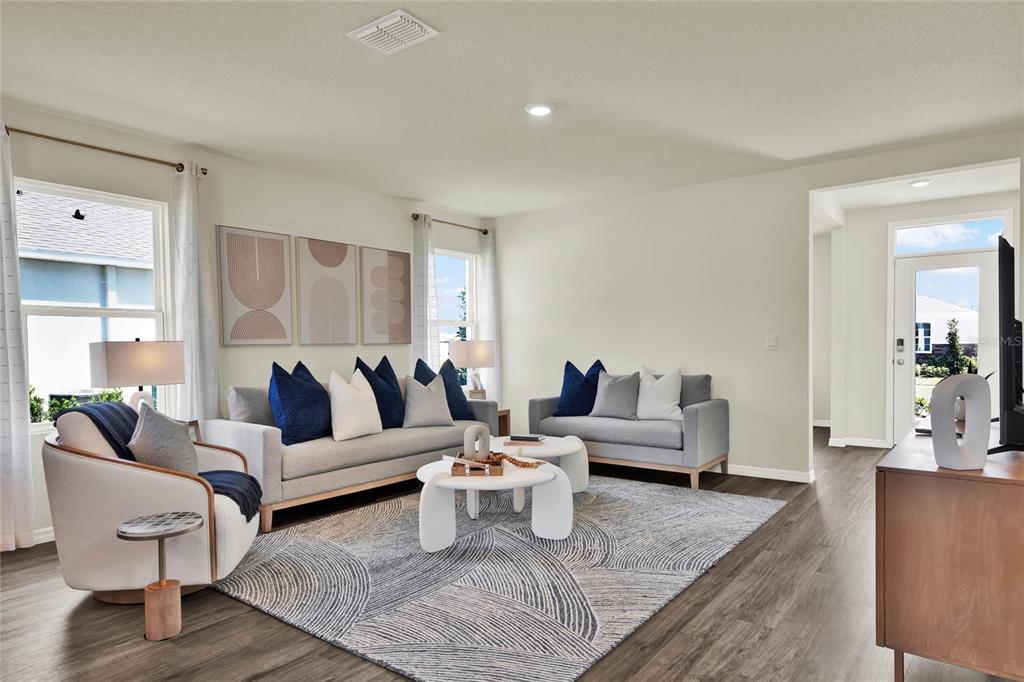 A living room features gray sofas, a patterned area rug, and a white accent chair — 5150 MARSHELDER STREET, APOPKA, FL