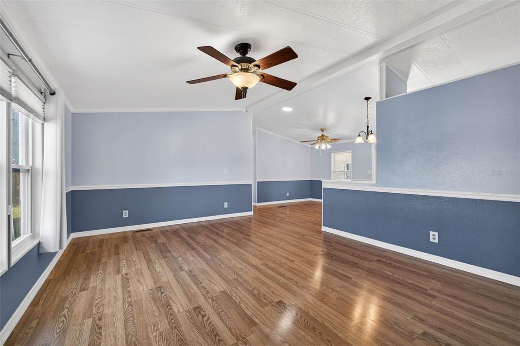 An empty room with wood-look flooring, two-tone blue walls, and two ceiling fans — 3904 WILLIAM HUME DRIVE, ZEPHYRHILLS, FL