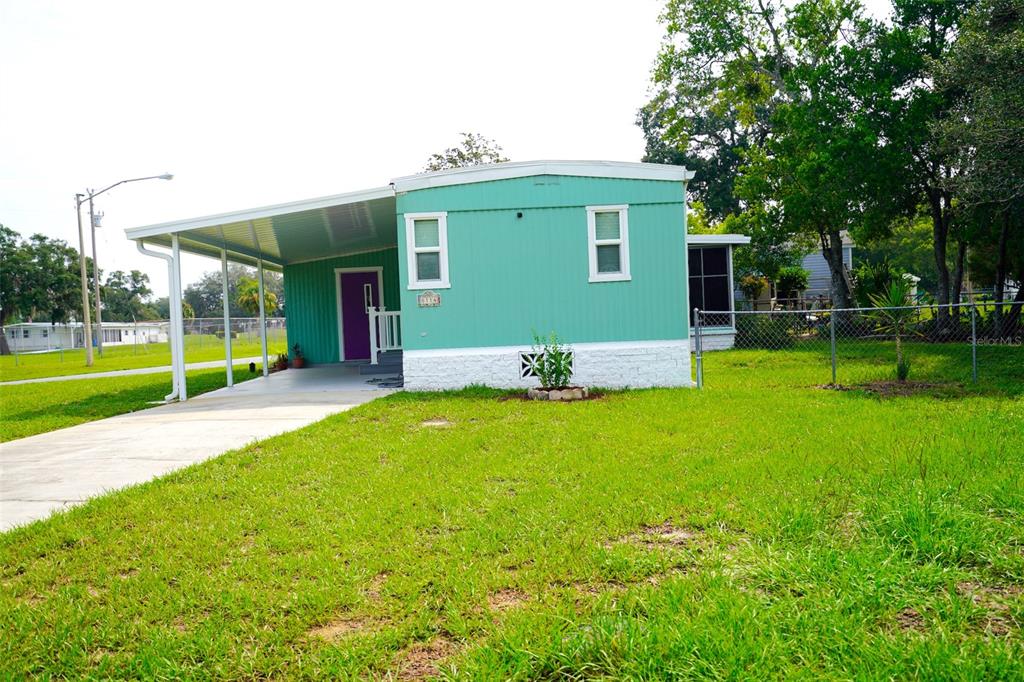 A teal mobile home with a white carport and a front lawn — 8114 WESTERN CIRCLE DRIVE, BROOKSVILLE, FL