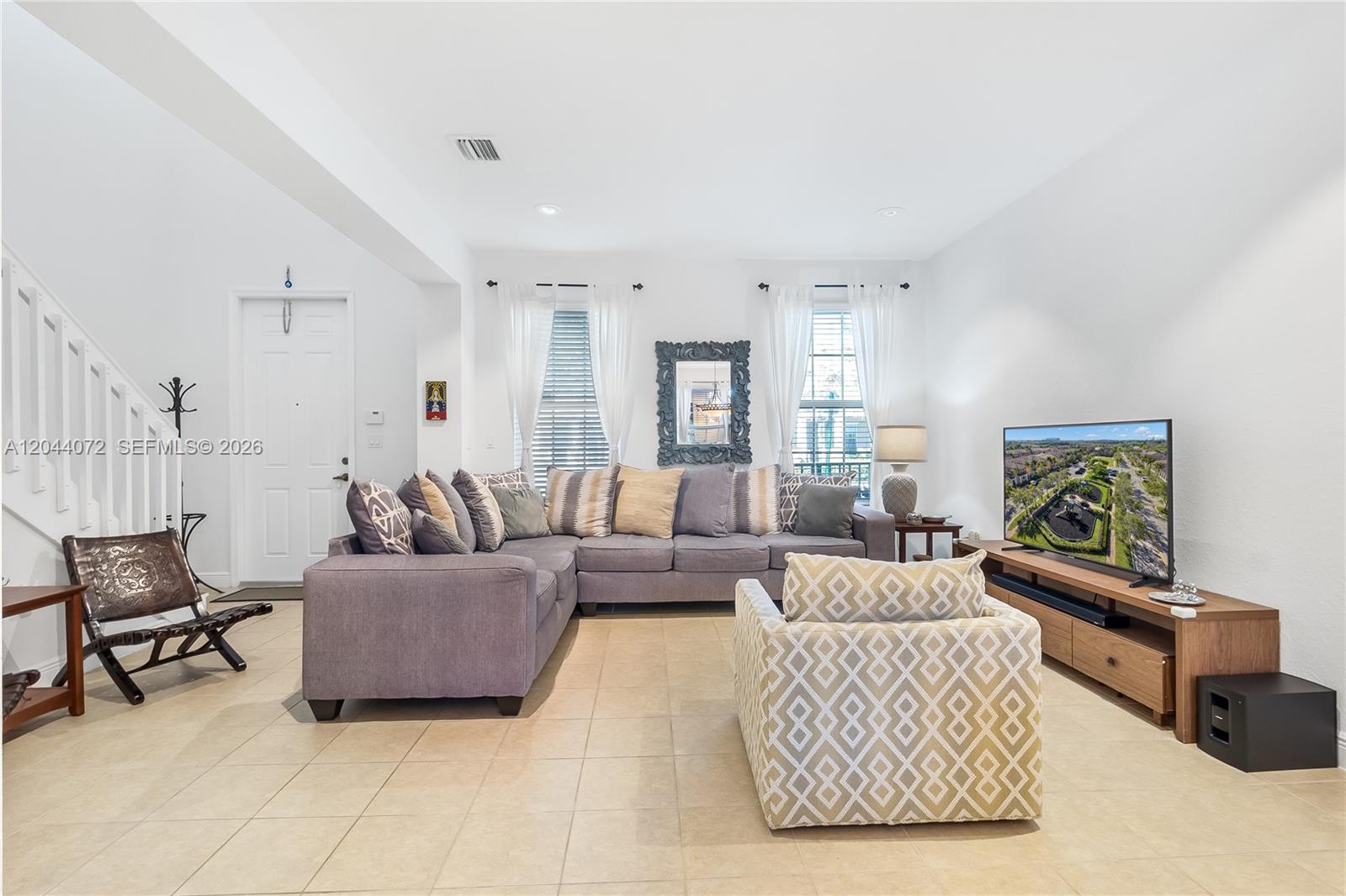 A living room features a large gray sectional sofa, a patterned armchair, and tile flooring — 1119 SW 147th Ave, Pembroke Pines FL 33027, PEMBROKE PINES, FL
