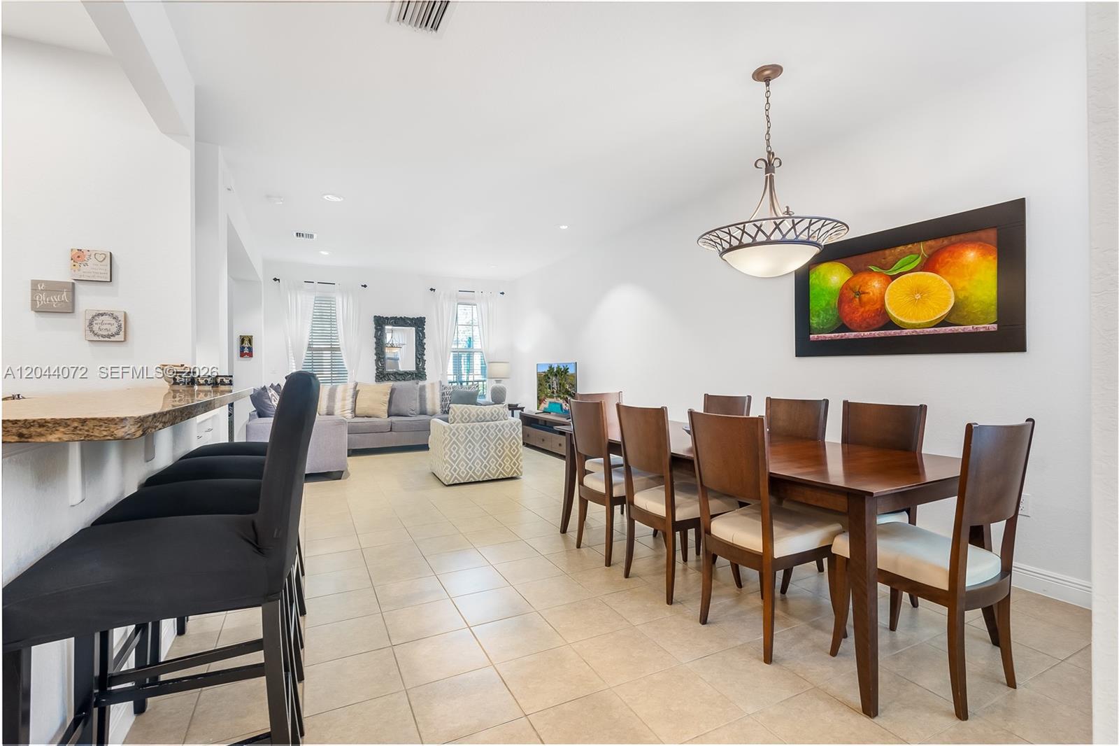 An open-concept living and dining area features tile flooring, a breakfast bar, and pendant lighting — 1119 SW 147th Ave, Pembroke Pines FL 33027, PEMBROKE PINES, FL