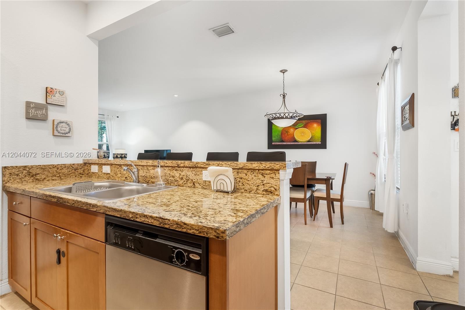 A kitchen with granite countertops and a stainless steel dishwasher overlooks a dining area — 1119 SW 147th Ave, Pembroke Pines FL 33027, PEMBROKE PINES, FL