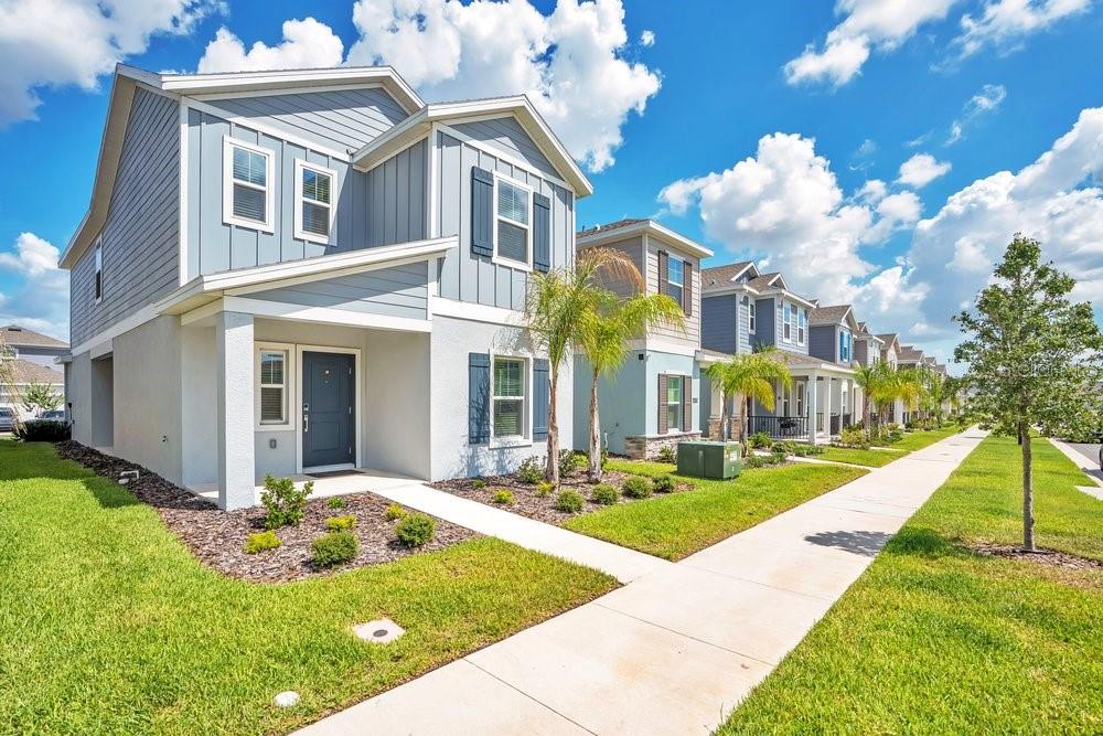 A two-story blue house with a front porch and sidewalk in a suburban neighborhood — 6176 SHAVASANA ROAD, CLERMONT, FL