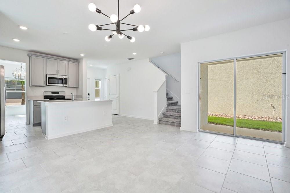 A modern kitchen with light gray cabinets and a white island opens to a living area — 6176 SHAVASANA ROAD, CLERMONT, FL