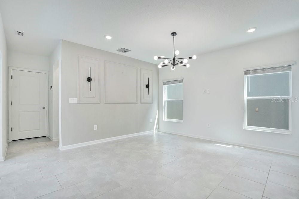 A bright dining room features light tile flooring, a modern chandelier, and decorative wall molding — 6176 SHAVASANA ROAD, CLERMONT, FL