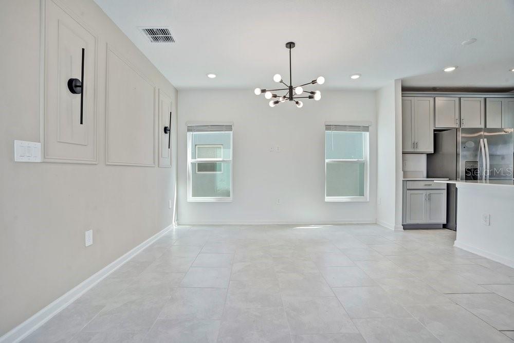 A dining area features light tile flooring, a modern chandelier, and decorative wall molding — 6176 SHAVASANA ROAD, CLERMONT, FL