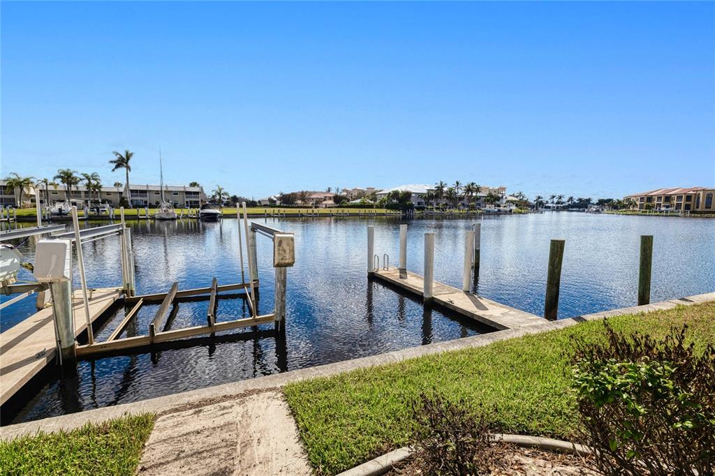 A canal view features boat docks, wooden pilings, and residential buildings under a clear blue sky — 3228 PURPLE MARTIN DRIVE UNIT 113, PUNTA GORDA, FL