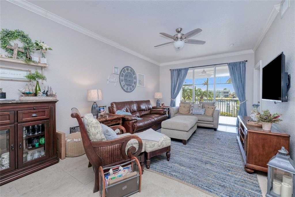 A living room features a brown leather sofa, a beige armchair, and a large area rug — 3228 PURPLE MARTIN DRIVE UNIT 113, PUNTA GORDA, FL