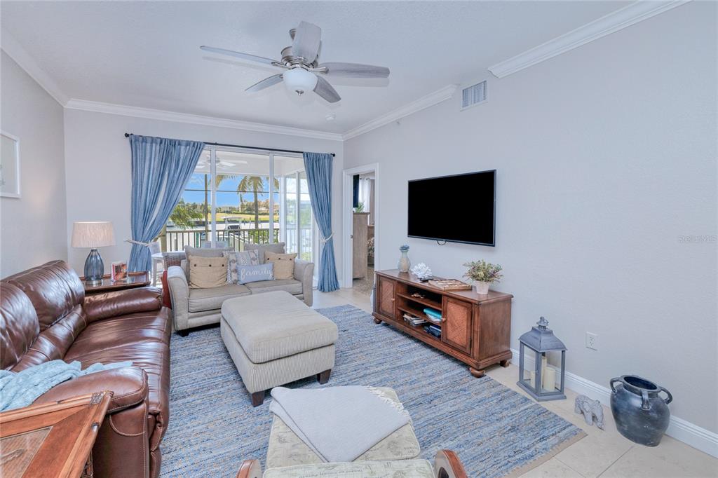 A living room features a brown leather sofa, a beige loveseat, and a television console — 3228 PURPLE MARTIN DRIVE UNIT 113, PUNTA GORDA, FL
