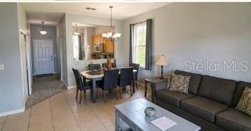 A living room and dining area feature tile flooring, a dark sofa, and kitchen pass-through — 2540 CALABRIA AVENUE, DAVENPORT, FL