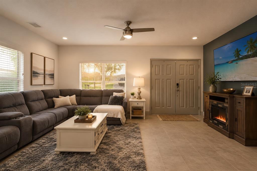 A living room features a gray sectional sofa, a white coffee table, and a fireplace console — 5328 BALDOCK AVENUE, SPRING HILL, FL