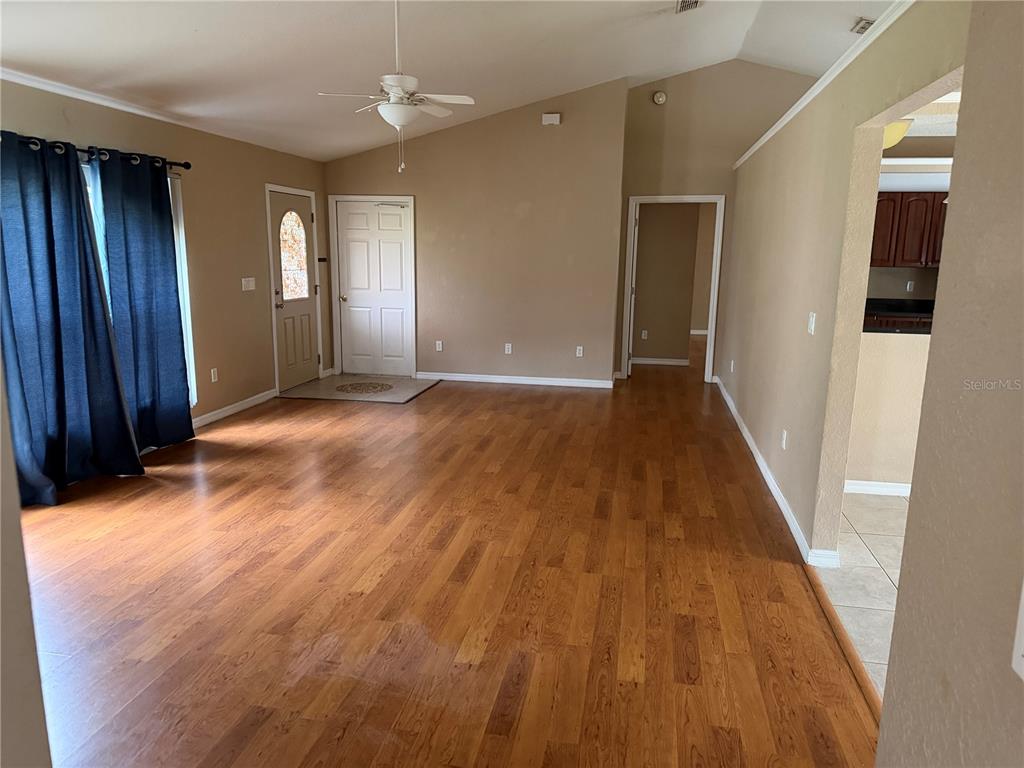 A living room with hardwood floors, a vaulted ceiling, and a doorway leading to a kitchen — 9371 SE 108TH PLACE, BELLEVIEW, FL