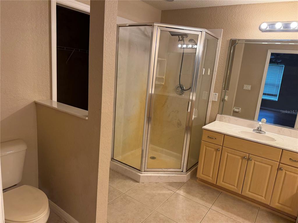 A bathroom features a corner shower, a light wood vanity, and a toilet — 9371 SE 108TH PLACE, BELLEVIEW, FL