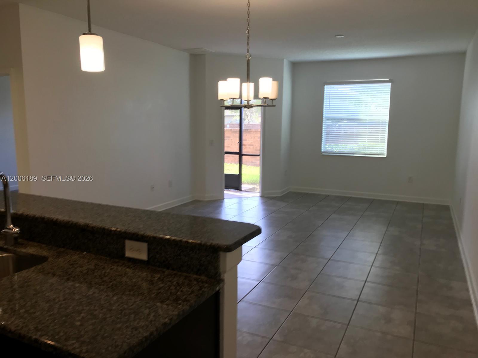 An open-concept kitchen and dining area features tile flooring, granite countertops, and a chandelier — 3348 RODRICK CIR, Orlando FL 32824, ORLANDO, FL