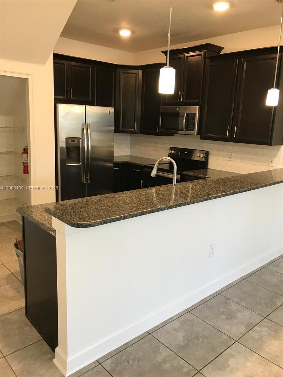A kitchen features dark wood cabinets, granite countertops, stainless steel appliances, and a breakfast bar — 3348 RODRICK CIR, Orlando FL 32824, ORLANDO, FL