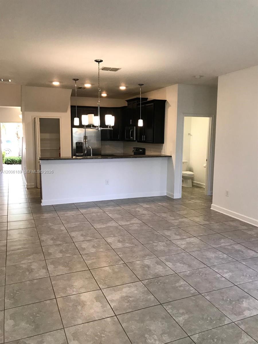 A kitchen with dark cabinets and a breakfast bar overlooks a tiled living area — 3348 RODRICK CIR, Orlando FL 32824, ORLANDO, FL