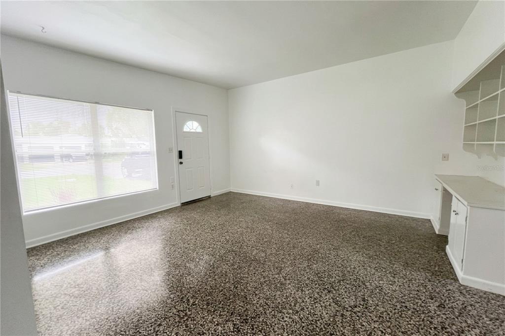 A room with white walls, a large window, a white door, and speckled epoxy flooring — 70-76 GRIGGS AVENUE, CASSELBERRY, FL